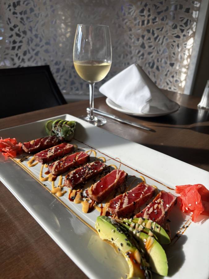 Sliced sesame-crusted tuna with avocado on a long white plate